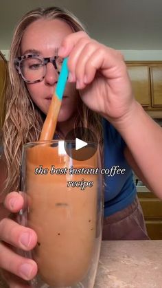 a woman is drinking from a glass with a straw in her mouth and the caption reads, the best instant coffee recipe