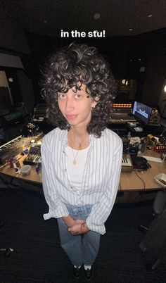 a woman with curly hair standing in front of a recording studio