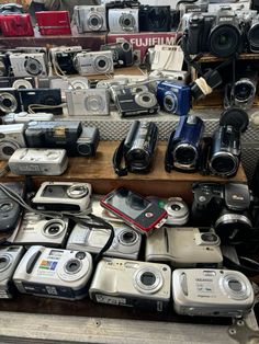 many different types of cameras on display in a store with wooden shelves full of them