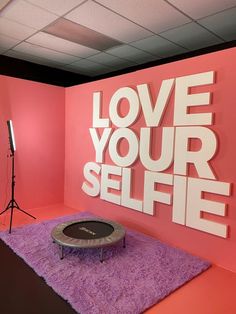 a pink room with a purple carpet and white letters on the wall that say love your selfie