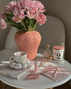 a pink vase filled with flowers sitting on top of a table next to a cup