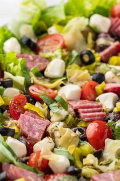 a salad with meat, olives, tomatoes, lettuce and other vegetables