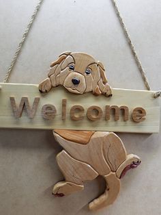 a wooden sign that says welcome with a dog hanging from it's front end