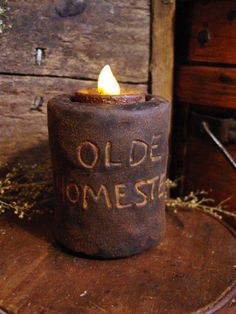 an old fashioned candle is sitting on top of a piece of wood with the words olde homes written on it