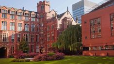 the building has many windows on it and is red brick with green grass in front