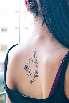 the back of a woman's shoulder with a flower tattoo on her left side