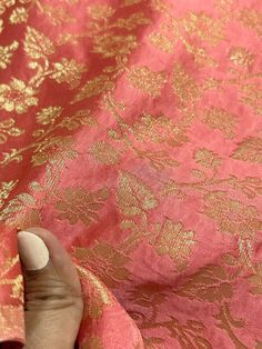 someone is sewing on the pink and gold brocaded fabric that has been sewn together