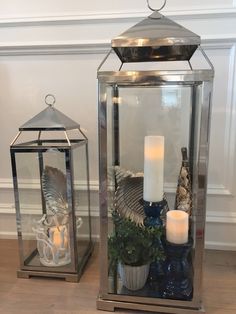 two glass lanterns with candles and other items on the floor next to eachother