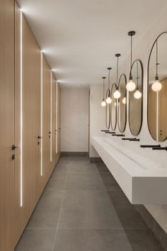 a long row of sinks in a bathroom with mirrors on the wall and lights hanging from the ceiling