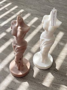 two small sculptures sitting on top of a wooden floor