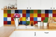 a kitchen with colorful tiles on the backsplash and wooden counter tops, along with white cabinets