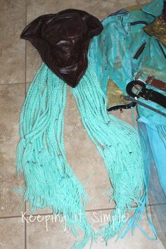 a blue scarf with fringes on the floor next to a brown purse and knife