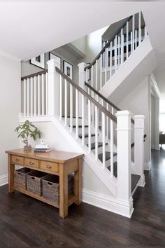 an entryway with a wooden table and white stairs