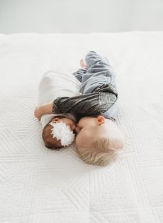 two babies laying on top of a bed next to each other