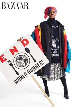 a woman is holding a sign that says end world hunger and wearing a head scarf