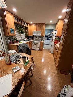 an open kitchen and dining room with wood flooring, cabinets, counter tops and appliances