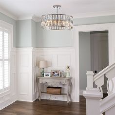 a chandelier hanging from the ceiling in a room with white walls and wood floors