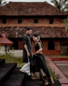 a man and woman standing next to each other in front of a building with stairs