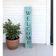 a welcome sign sitting next to a potted plant