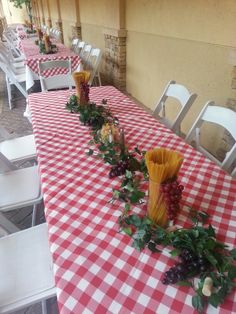 the table is set up with red and white checkered tables cloths, vases filled with flowers and greenery