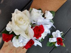 two white and red flowers are on the wrist of a woman