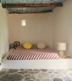 a bed sitting under a wooden beam next to a lamp on top of a table