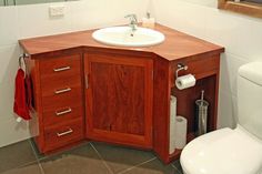 a bathroom with a sink, toilet and mirror in it's corner cabinet next to the toilet