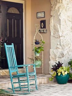 a blue rocking chair sitting in front of a door next to a potted plant