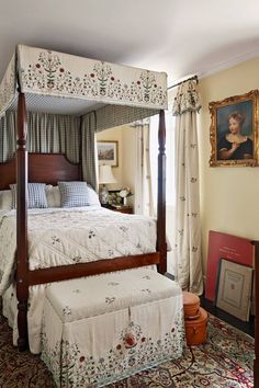 a four poster bed in a bedroom next to a window