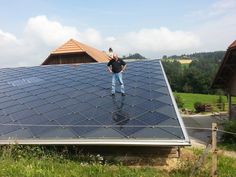 a man standing on the roof of a house with solar panels covering his entire body