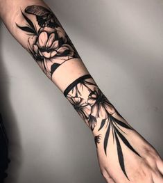 a person's arm with black ink flowers on it and an arrow in the middle