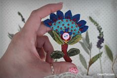 a hand holding a small blue and red flower