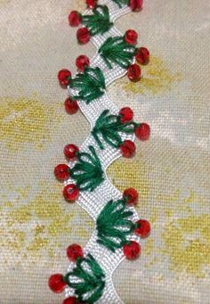 a white lace with red berries and green leaves is on a tablecloth that has been sewned