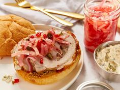 a white plate topped with food next to a bowl of coleslaw and bread