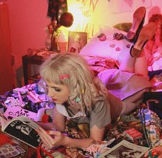 a woman laying on top of a bed next to a pile of books and magazines