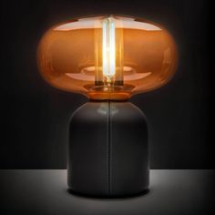 a table lamp that is on top of a black surface with a light shining in the middle