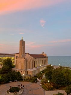 an aerial view of a building with a clock tower and the ocean in the background