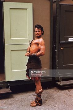 a man in roman garb standing next to an open door and looking at the camera