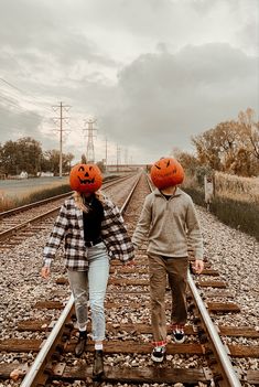 two people with pumpkin heads walking down train tracks