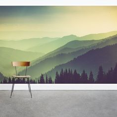 a chair sitting in front of a wall with mountains and trees painted on the side