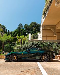 a black and green sports car parked in front of a building with plants on it