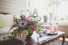 a table with flowers and candles on it in front of a couch, coffee table