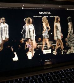 a laptop computer displaying a fashion show on it's display screen, with models walking down the runway