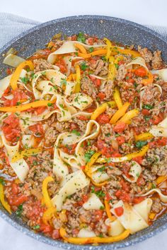 a pan filled with pasta, meat and veggies on top of a table