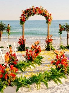 an outdoor ceremony set up on the beach with flowers and greenery at the altar