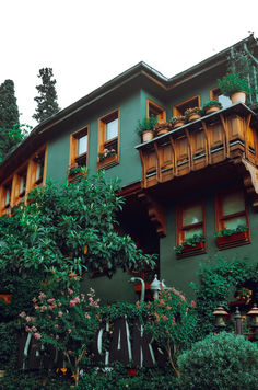 a green building with lots of windows and plants growing on the side of it's sides