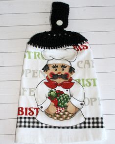 a kitchen towel hanging on the wall with a chef holding a potted plant in it