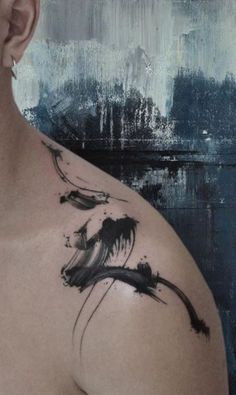 a close up of a person's chest with black ink on it and an abstract painting in the background