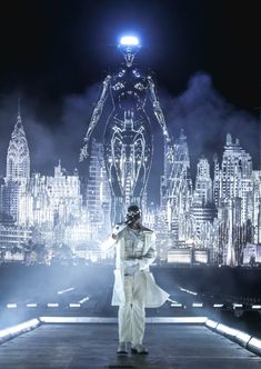 a man standing on top of a stage in front of a city