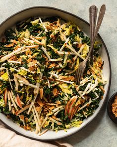 a bowl filled with salad and two spoons